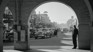 a black and white photo of a man standing in the middle of a street